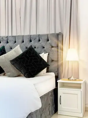 a bed with a gray headboard and a table with a lamp at One BedRoom near Beach and Metro in Dubai Marina Z1011 in Dubai