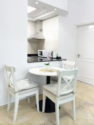 a white kitchen with a table and two chairs at One BedRoom near Beach and Metro in Dubai Marina Z1011 in Dubai