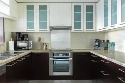 a kitchen with white cabinets and a stove top oven at Kinfolk Homes - No 1 Family Stay, Partial Burj Khalifa Fountain View in Dubai