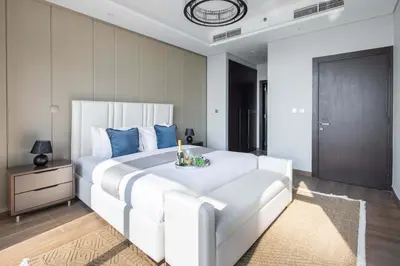 a bedroom with a large white bed with blue pillows at Frank Porter - Nobles Tower in Dubai