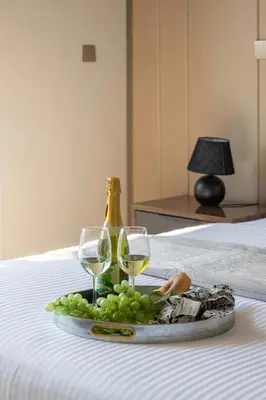 a tray of grapes and wine glasses on a bed at Frank Porter - Nobles Tower in Dubai