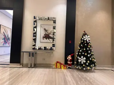 a christmas tree in a building with a child standing next to it at Damac Hills in Dubai