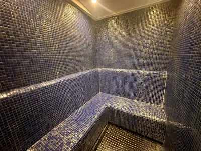 a bathroom with a blue tiled shower with a tub at Damac Hills in Dubai