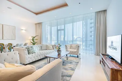 a living room with white furniture and a large window at Palm Home next to Nakheel Mall with Private Beach in Dubai
