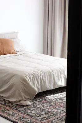 a bed with white sheets on a rug next to a window at Cozy 1 Bedroom Apartment in Dubai