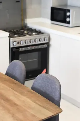 a kitchen with a table with two chairs and an oven at Cozy 1 Bedroom Apartment in Dubai