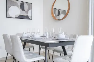 a dining room table with white chairs and a mirror at Premium 3-bedroom with Direct Beach Access in JBR in Dubai