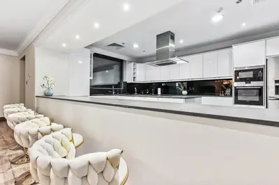 a kitchen with white cabinets and a bar with white chairs at Luxury 6BR JBR Penthouse Panoramic Sea Views, Steps to Marina Beach & The Walk in Dubai