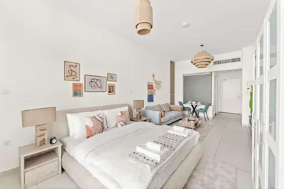 a white bedroom with a large bed and a living room at Silkhaus Offshore Studio in Palm Views East Tower in Dubai