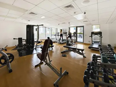 a gym with tread machines and people in the background at Silkhaus 1BR Downtown Heart in Emaar Tower in Dubai
