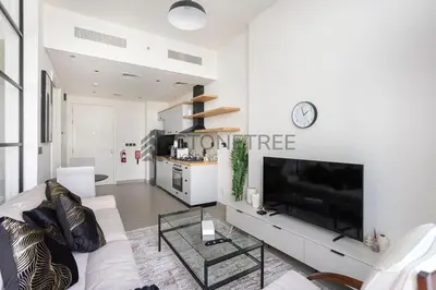 a white living room with a large tv and a couch at Modern 1BR at Collective Tower 1 Near Hills Mall in Dubai