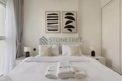 a bedroom with a white bed with two towels on it at Modern 1BR at Collective Tower 1 Near Hills Mall in Dubai