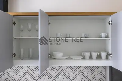 a white cabinet with dishes and glasses on it at Bright 1BR at Collective Tower 1 Near Hills Mall in Dubai