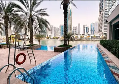 a large swimming pool with palm trees and a hotel at Blakely 2BR Lakeview Retreat - Open Balcony and Marina Views in Dubai