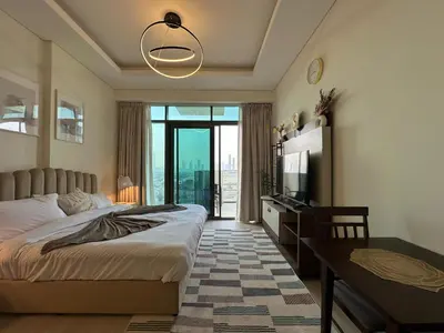 a bedroom with a bed and a table and a television at Sunset Haven Chic Creek Studio in Dubai