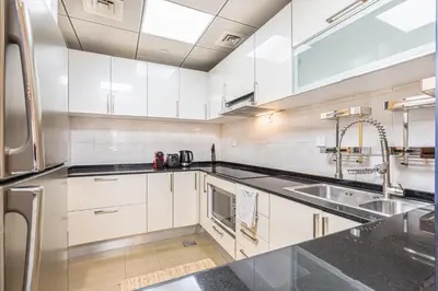 a kitchen with white cabinets and stainless steel appliances at Elegant Home in the Heart of Marina in Dubai