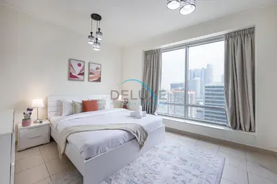 a white bedroom with a bed and a large window at Tranquil 1BR in Burj Views Tower B, Downtown by Deluxe Holiday Homes in Dubai