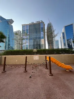a playground in front of a city with tall buildings at Stylish 1BR in the heart of Dubai - easy walk by the canal in Dubai