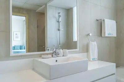 a white bathroom with a sink and a mirror at Beachfront Bliss Luxurious 3-BR Stay in JBR in Dubai