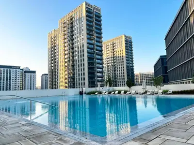 a large swimming pool in a city with tall buildings at Elegant & Bright 1BR Getaway Near Dubai Hills Park in Dubai