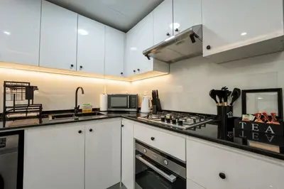 a kitchen with white cabinets and a stove top oven at Dubai Marina - 1 BHK Elegant Apartment in Dubai