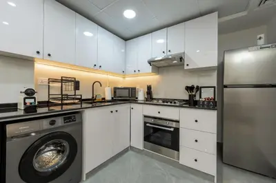 a kitchen with white cabinets and a washer at Dubai Marina - 1 BHK Elegant Apartment in Dubai