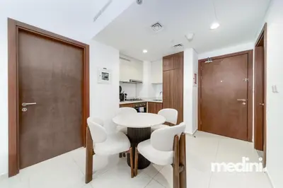 a room with a table and chairs and a kitchen at 10 min from Burj Khalifa - Sauna - Gym - Damac Reva in Dubai