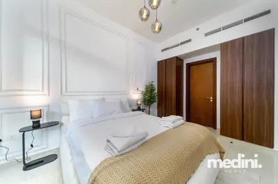 a white bedroom with a large bed and a window at 10 min from Burj Khalifa - Sauna - Gym - Damac Reva in Dubai