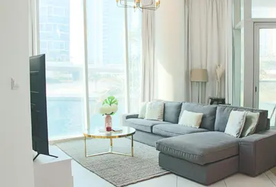 a living room with a couch and a tv at 2 Bedroom Apartment with Spacious Private Garden in Dubai Marina in Dubai