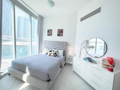 a white bedroom with a bed and a mirror at 2 Bedroom Apartment with Spacious Private Garden in Dubai Marina in Dubai