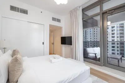 a bedroom with a white bed and a large window at StayShort - Bright and Airy 1-Bedroom Apartment Perfect for 4 in Dubai Marina in Dubai