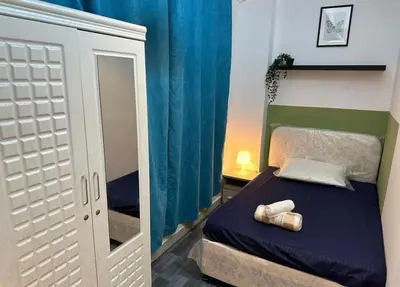a small bedroom with a bed and a mirror at Lavish Double Partition Room in Barsha Heights in Dubai