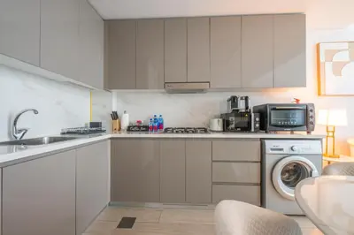 a kitchen with white cabinets and a washer and dryer at Luxuriöser Aufenthalt mit Blick auf den Burj Khalifa in Dubai