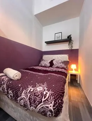 a bedroom with a bed with a purple accent wall at Calm Partition Room Near Internet City Metro in Dubai