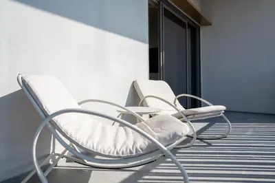 two white chairs sitting on a balcony at Modern 1-Bedroom Retreat in MBR City in Dubai