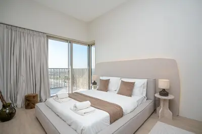 a white bedroom with a large bed and a large window at Modern 1-Bedroom Retreat in MBR City in Dubai
