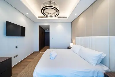 a bedroom with a white bed with a tv on the wall at Luxe 3BDR Panoramic Burj Khalifa Views Business Bay in Dubai