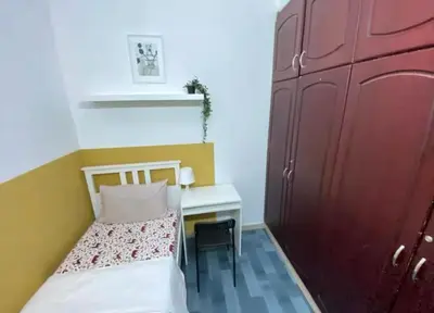 a small room with a bed and a desk and a red door at City Stay Partition Room in al Barsha 1 Near Metro in Dubai