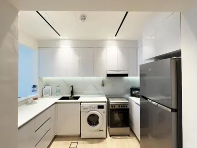 a kitchen with white cabinets and a washer at Luxurious new 1 bedroom with Balcony and New Building in Dubai