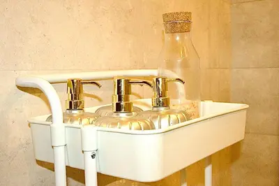 a sink with two faucets and a glass bottle at Luxuriously Designed Spacious Studio In JVC in Dubai