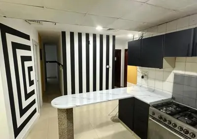 a kitchen with black cabinets and a counter top at Compact Partition Room in Barsha in Dubai