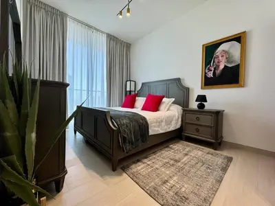 a bedroom with a bed with red pillows and a plant at Chic & Modern 1br In Jvc With Full Amenities in Dubai
