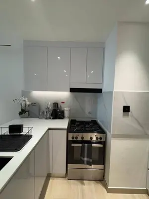 a white kitchen with a stove and white cabinets at New 1br Apt Jvc Pool View, Balcony & Parking in Dubai