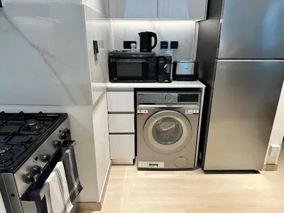 a kitchen with a washing machine and a microwave at New 1br Apt Jvc Pool View, Balcony & Parking in Dubai