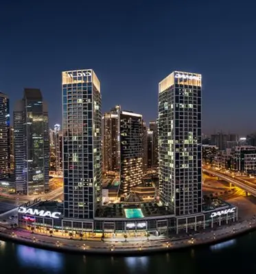 a large city with tall skyscrapers at night at Damac Maison Prive - Blue Ocean Holiday Homes in Dubai