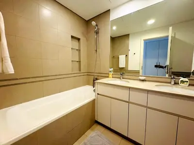 a bathroom with a tub and a sink and a mirror at 02 Bedroom Apartment in Townsquare in Dubai