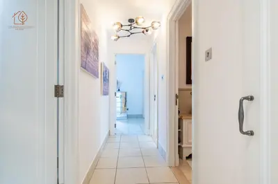 a hallway with white walls and a tile floor and a chandelier at Cozy Old Town 2-Bed Apartment with Burj Khalifa Views 202RH-2 in Dubai