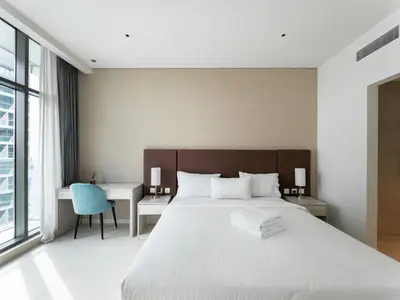 a bedroom with a large white bed and a desk at 1BR Palm Jumeirah - Rooftop Pool & Beach Access in Dubai