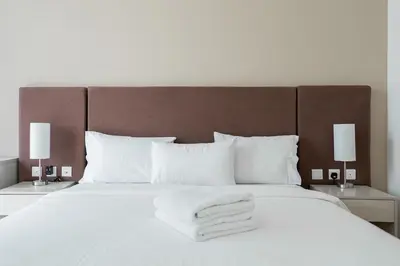 a large white bed with white towels on it at 1BR Palm Jumeirah - Rooftop Pool & Beach Access in Dubai