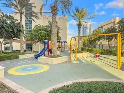 a playground in a park with palm trees at Cozy Studio with Scenic Canal Views in Dubai